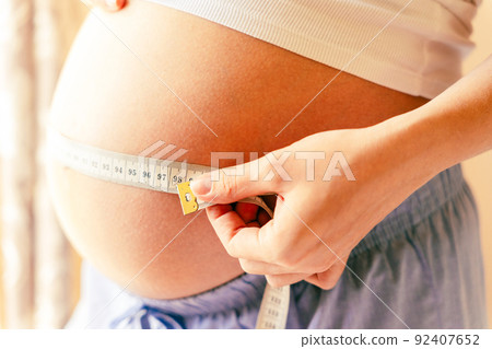 Measure belly pregnancy woman. Happy young pregnant woman with tape measuring belly. Concept maternity, pregnancy, childbirth. 92407652