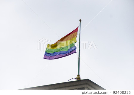 Close Up rainbow gay pride flag outside on a street. Symbol of the Lesbian Bisexual Transgender LGBT community waving in wind against cloudy sky. Social movement for freedom and equliaty. Copy Space Close Up rainbow gay pride flag outside on a street. Symbol of the Lesbian Bisexual Transgender LGBT community waving in wind against cloudy sky. Social movement for freedom and equliaty. Copy Space 92408235