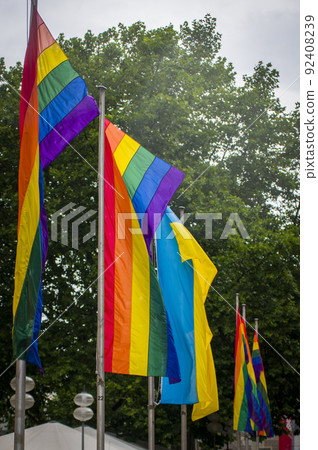 Close Up rainbow gay pride flag outside on a street. Symbol of the Lesbian Bisexual Transgender LGBT community waving in wind against cloudy sky. Social movement for freedom and equliaty. Copy Space 92408239
