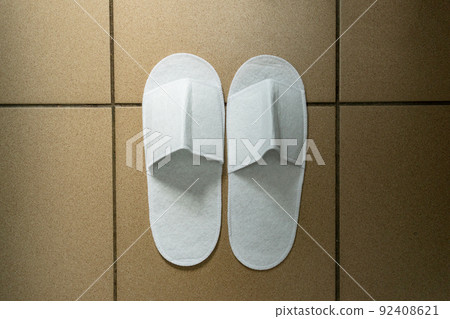 Disposable white slippers, guest shoes on the floor of the hotel or medical ward. 92408621