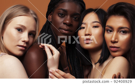 young pretty african and caucasian women posing cheerful together on brown background, lifestyle diverse nationality people concept close up young pretty african and caucasian women posing cheerful together on brown background, lifestyle diverse nationality people concept close up 92408929