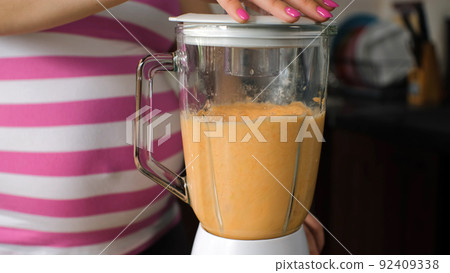 Close-up of Pregnant Woman Preparing Healthy Smoothie Drink from Carrot, Oranges and Apples with Blender 92409338