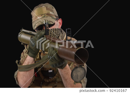 Private Military Contractor firing RPG (rocket propelled grenade) - soviet bazooka type grenade launcher. Flame and smoke on background. 92410167