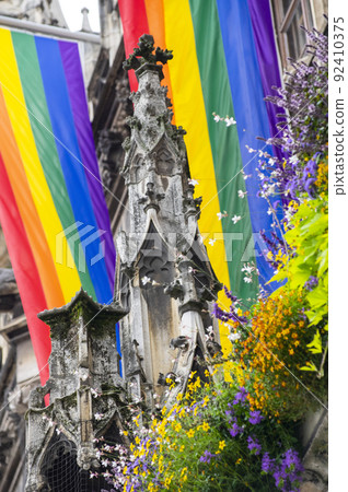 Close Up rainbow gay pride flag outside on a street. Symbol of the Lesbian Bisexual Transgender LGBT community waving in wind against cloudy sky. Social movement for freedom and equliaty. Copy Space 92410375