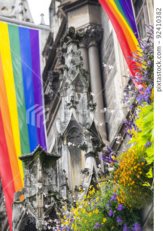 Close Up rainbow gay pride flag outside on a street. Symbol of the Lesbian Bisexual Transgender LGBT community waving in wind against cloudy sky. Social movement for freedom and equliaty. Copy Space 92410382