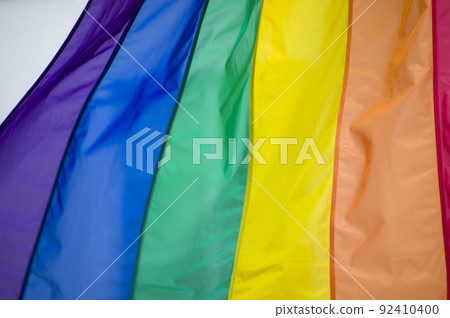 Close Up rainbow gay pride flag outside on a street. Symbol of the Lesbian Bisexual Transgender LGBT community waving in wind against cloudy sky. Social movement for freedom and equliaty. Copy Space Close Up rainbow gay pride flag outside on a street. Symbol of the Lesbian Bisexual Transgender LGBT community waving in wind against cloudy sky. Social movement for freedom and equliaty. Copy Space 92410400