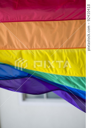 Close Up rainbow gay pride flag outside on a street. Symbol of the Lesbian Bisexual Transgender LGBT community waving in wind against cloudy sky. Social movement for freedom and equliaty. Copy Space 92410418