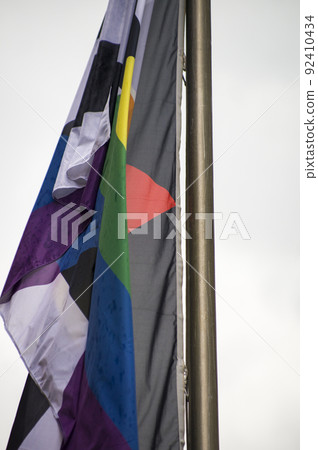 Close Up rainbow gay pride flag outside on a street. Symbol of the Lesbian Bisexual Transgender LGBT community waving in wind against cloudy sky. Social movement for freedom and equliaty. Copy Space 92410434