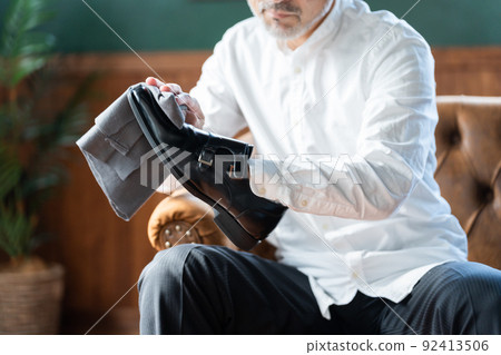 Senior man shining shoes at home 92413506