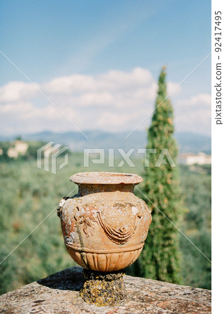 Clay amphora on a stone fence in the garden. Florence, Italy Clay amphora on a stone fence in the garden. Florence, Italy 92417495