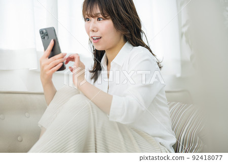 A woman watching a smartphone at home 92418077