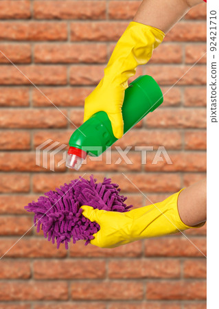 Women's hands in protective gloves with bottle of washing liquid. Women's hands in protective gloves with bottle of washing liquid. 92421710
