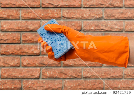 Woman's hand in protective glove with sponge. 92421739