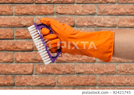 Woman's hand in protective glove with brush. Woman's hand in protective glove with brush. 92421745