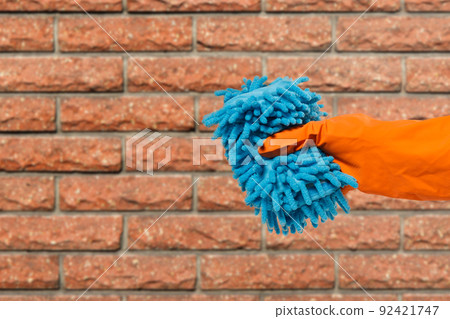 Woman's hand in protective glove with rag. Woman's hand in protective glove with rag. 92421747
