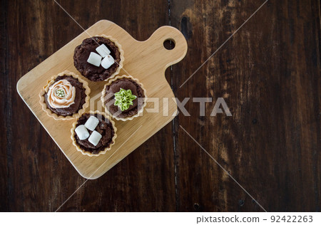 Assorted mini brownie tart serving on the wooden table. High angle view. Assorted mini brownie tart serving on the wooden table. High angle view. 92422263
