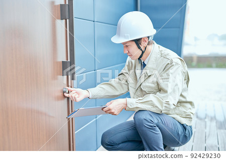 Young man in work clothes checking the door Young man in work clothes checking the door 92429230