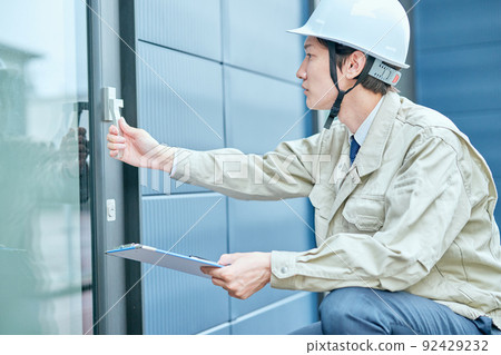 Young man in work clothes checking the door Young man in work clothes checking the door 92429232