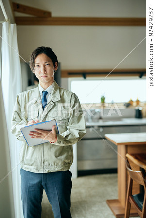 A salesman in work clothes standing in front of the kitchen with a binder A salesman in work clothes standing in front of the kitchen with a binder 92429237