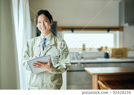 A salesman in work clothes standing in front of the kitchen with a binder A salesman in work clothes standing in front of the kitchen with a binder 92429239