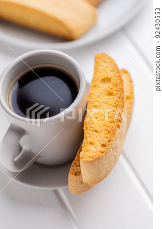 Sweet anicini cookies and coffee cup. Italian biscotti with anise flavor on white table. Sweet anicini cookies and coffee cup. Italian biscotti with anise flavor on white table. 92430553