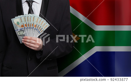 Hand holds 100 US dollar bills money banknotes against flag of South Africa background Hand holds 100 US dollar bills money banknotes against flag of South Africa background 92433877