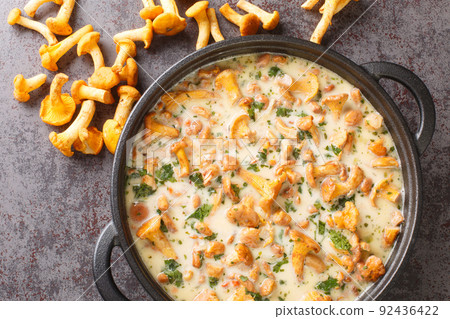Stewed chanterelle mushrooms with cheese, garlic, cream and herbs close-up in a pan. horizontal top view Stewed chanterelle mushrooms with cheese, garlic, cream and herbs close-up in a pan. horizontal top view 92436422