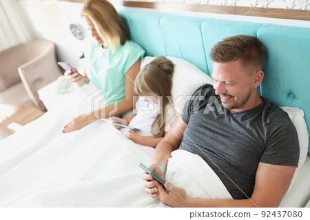 Family stare in smartphone, morning in bed with devices, kill time 92437080