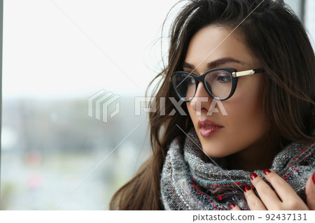 Young beautiful woman in scarf, warming hands, pensive look away, view from window Young beautiful woman in scarf, warming hands, pensive look away, view from window 92437131