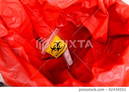 Infectious biohazard specimen bag of covid-19 test in the red infectious waste bin 92439501