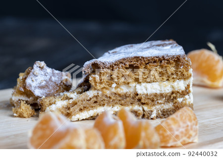 a piece of honey cake with vanilla cream and citrus tangerines 92440032