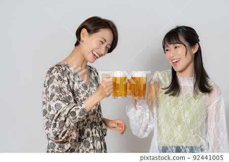 兩個喝啤酒的中年婦女在白色背景 92441005