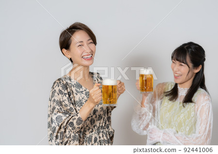 兩個喝啤酒的中年婦女在白色背景 92441006