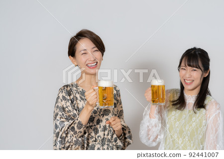 兩個喝啤酒的中年婦女在白色背景 兩個喝啤酒的中年婦女在白色背景 92441007