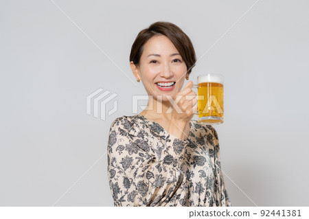 One middle-aged woman drinking beer on a white background One middle-aged woman drinking beer on a white background 92441381