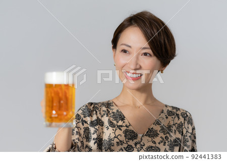 One middle-aged woman drinking beer on a white background 92441383