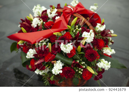 Flowers on monument. Artificial flowers on memorial. Solemn wreath on day of mourning. 92441679