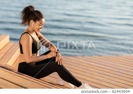 Black woman looking at smart watch, choosing music for workout 92443604