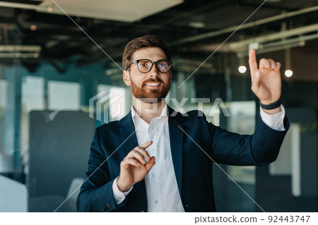 Successful entrepreneur in formalwear selecting something on virtual screen, standing in modern office interior, mockup Successful entrepreneur in formalwear selecting something on virtual screen, standing in modern office interior, mockup 92443747
