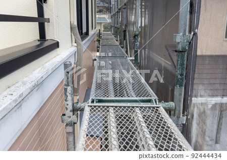 Scaffolding installed for 25-year-old detached roof exterior wall construction 92444434