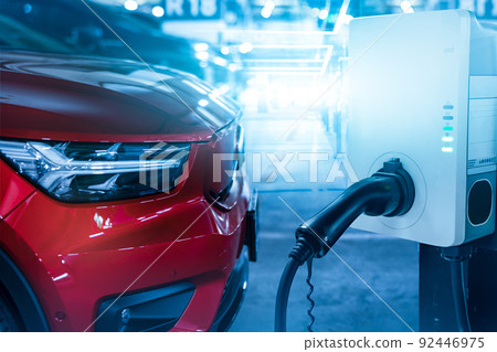 Car charging at electric car charging station. Electric vehicle charger station for charge EV battery. Charging point at car parking lot. Clean and sustainable energy. Commercial EV charging point. 92446975