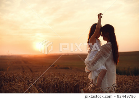 Family in a summer field. Sensual photo. Cute little girl. Woman in a white dress. 92449786