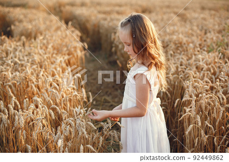 Child in a summer wheat field. Little girl in a cute white dress. Child in a summer wheat field. Little girl in a cute white dress. 92449862
