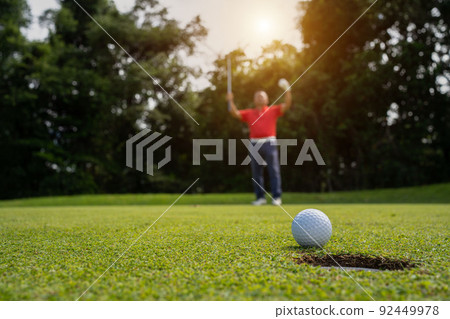 Golfer putting ball on the green golf, lens flare on sun set evening time. Golfer putting ball on the green golf, lens flare on sun set evening time. 92449978