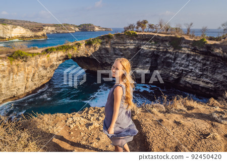 Young woman tourist near Broken Beach in Nusa Penida, Indonesia Angel's BillaBong Beach. Popular tourist destination Bali 92450420