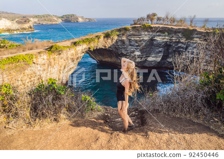 Young woman tourist near Broken Beach in Nusa Penida, Indonesia Angel's BillaBong Beach. Popular tourist destination Bali Young woman tourist near Broken Beach in Nusa Penida, Indonesia Angel's BillaBong Beach. Popular tourist destination Bali 92450446