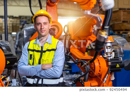 Portrait smart engineer man working with advance robotic machine weling in heavy industry. Portrait smart engineer man working with advance robotic machine weling in heavy industry. 92450494
