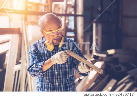 Senior Carpenter man Wood worker working hand made furniture in shop factory industry. male wooden craftsman builder working in workshop. 92450718