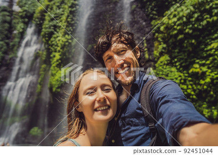 Loving couple at the Sekumpul waterfalls in jungles on Bali island, Indonesia. Bali Travel Concept Loving couple at the Sekumpul waterfalls in jungles on Bali island, Indonesia. Bali Travel Concept 92451044