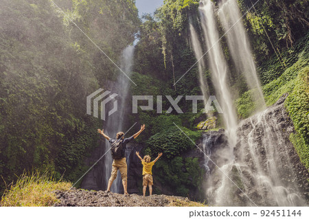 Dad and son at the Sekumpul waterfalls in jungles on Bali island, Indonesia. Bali Travel Concept Dad and son at the Sekumpul waterfalls in jungles on Bali island, Indonesia. Bali Travel Concept 92451144